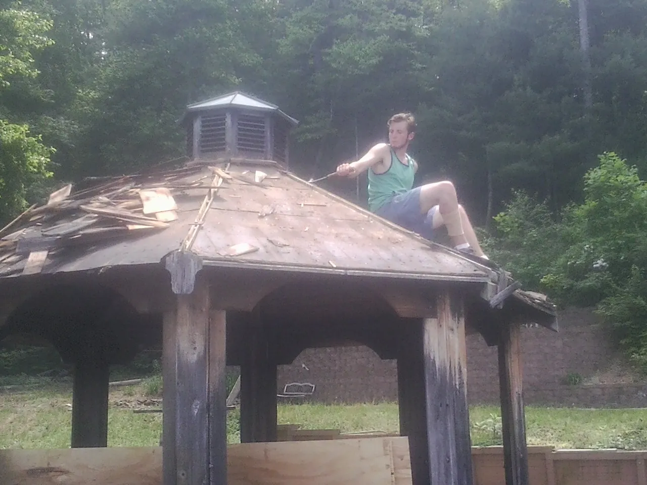 Tearing the old roof off a wooden gazebo before new shakes in Three Lakes
