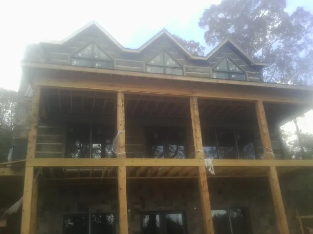Dormers and porch framing on a large log home under construction — Roof Coating work by our crew in Three Lakes