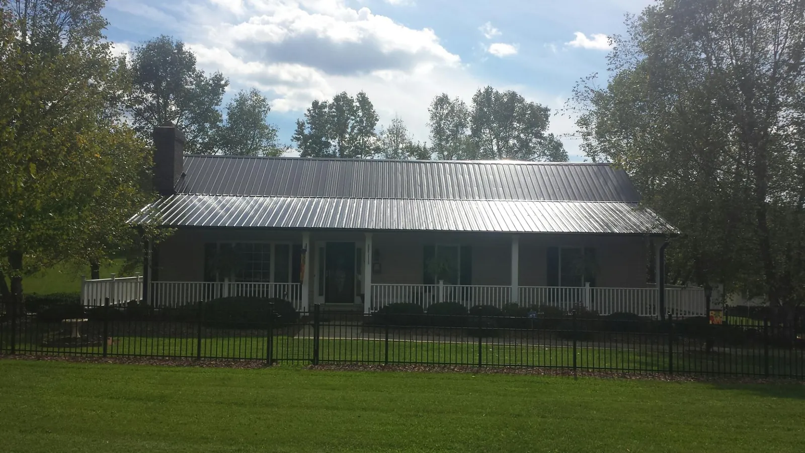 Gray metal roof on a brick ranch with a full width front porch — Gutter Guard Installation work by our crew in Three Lakes