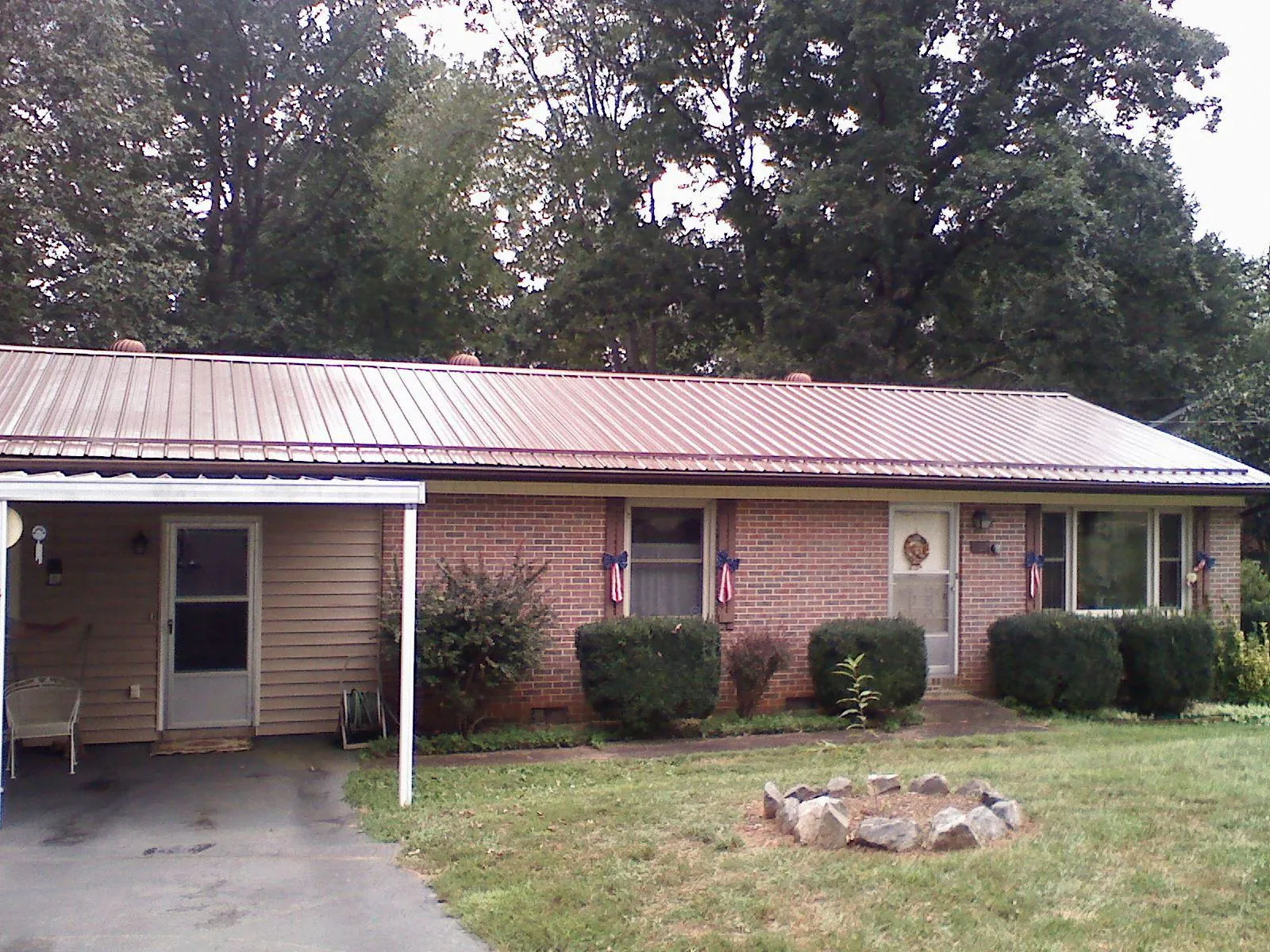 Bronze metal roof and carport on a brick ranch home — Roof Repair work by our crew in Three Lakes
